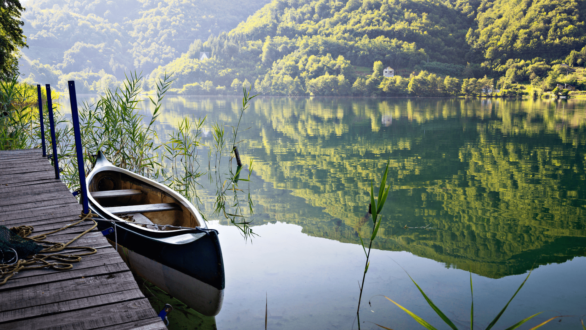 Calm lake with a small boat and still water reflecting trees, symbolising self-trust and inner clarity for empaths